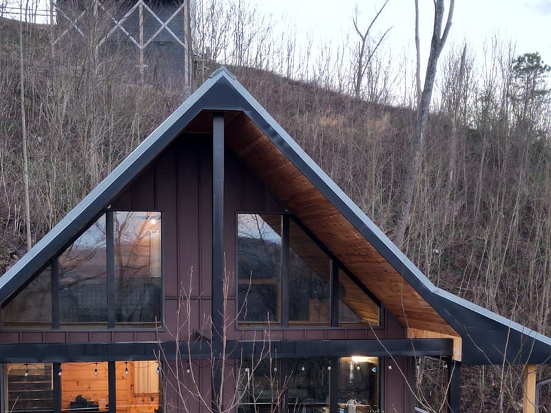 Straight-on view of the A-frame front gable, the metal roof running symmetrically to both eaves
