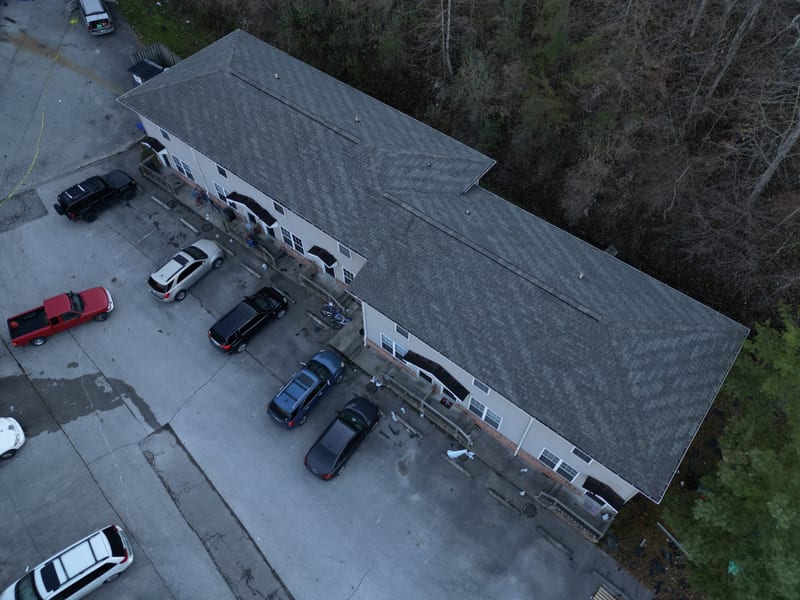 Completed new gray shingle roof on one building of the apartment complex at dusk