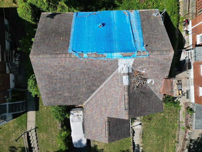 Before: damaged roof with blue tarp emergency cover