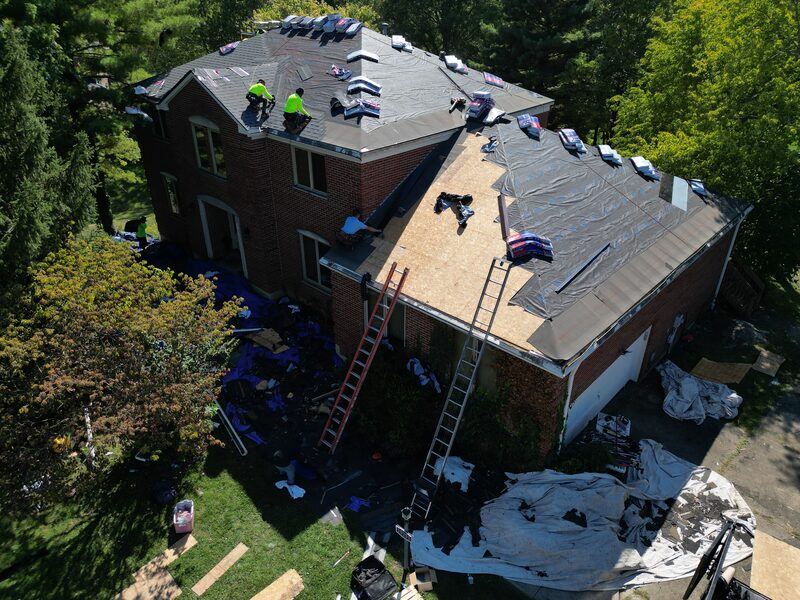 During: large brick home mid-tearoff with crew working