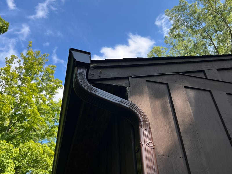 Upward view along the gutter line into the downspout elbow at the gable corner