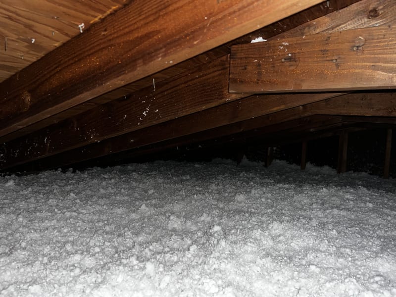 Inside the attic: rafter bays over fresh blown-in insulation after the ventilation fix