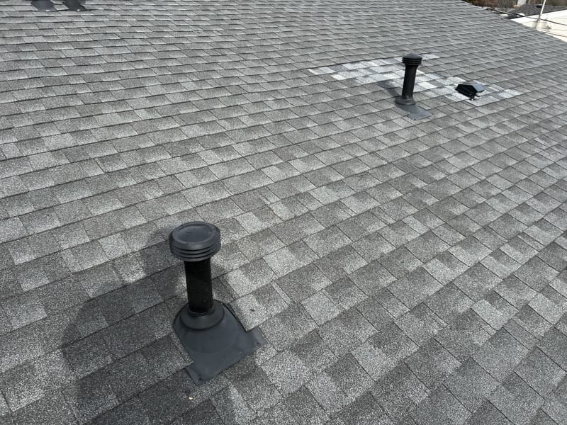 Close-up of two new black Roofivent vents installed on the fresh shingle slope