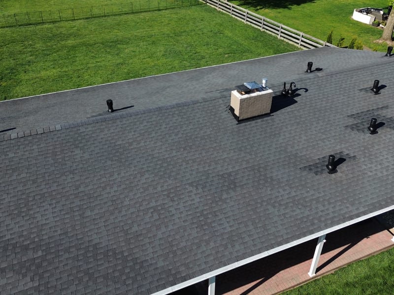 Wide aerial of the finished roof with the new vents down both slopes and fresh shingle patches at every penetration