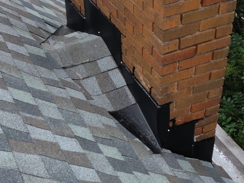 New black step and counter-flashing worked into the brick chimney beside the designer-blend shingles