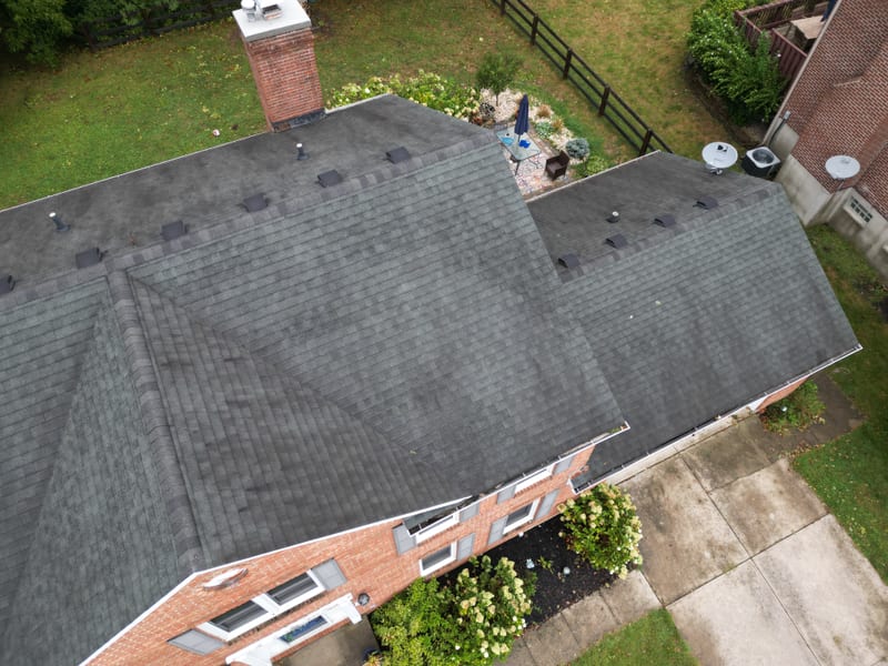 Wider overhead of the same brick home showing the rear patio, garage wing and complete new roof
