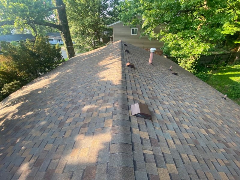 The finished roof looking up the ridge line in warm multi-tone dimensional shingle with new vents and pipe boot