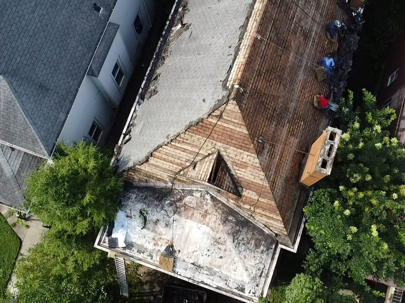 Angled overhead view of the stripped slopes, dormer opening, and the chimney rebuilt between fresh wood forms
