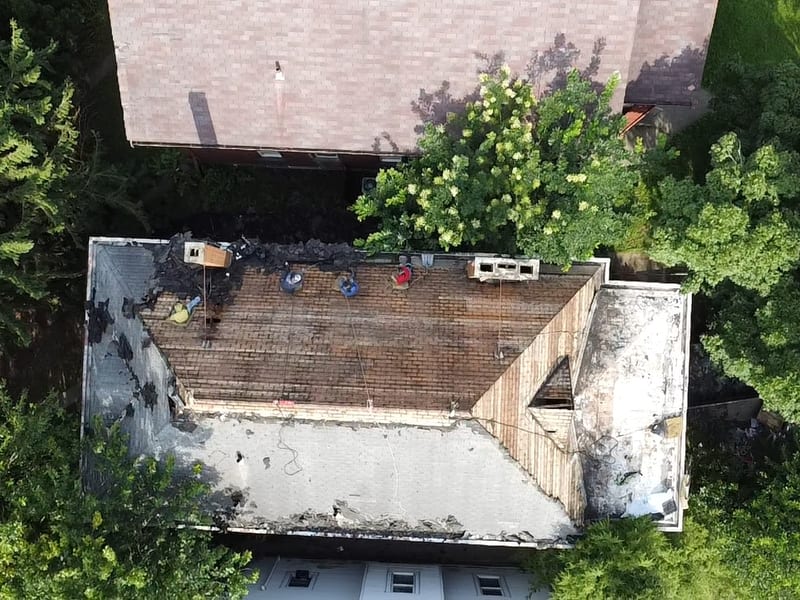 Whole-house top-down view with the front slope stripped to plank decking and the rear slope still shingled