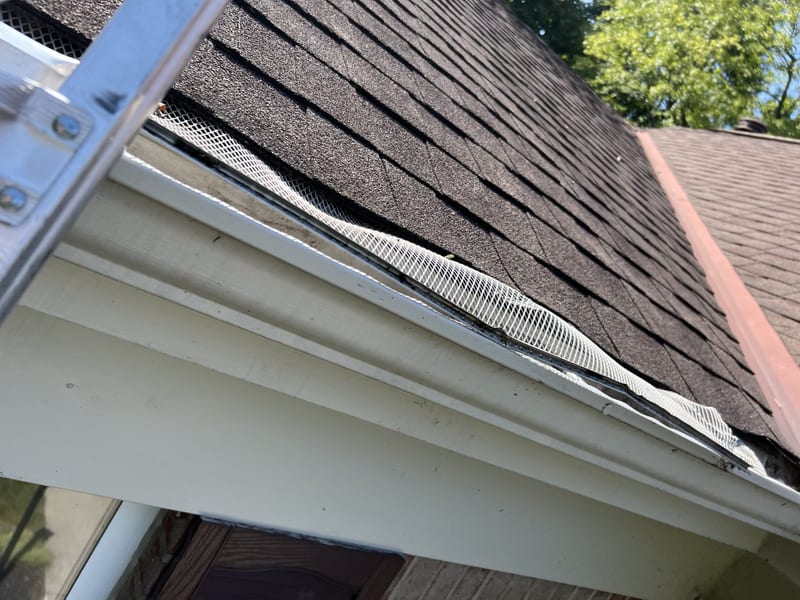 New seamless gutter with micromesh leaf screen installed along a shingled roofline