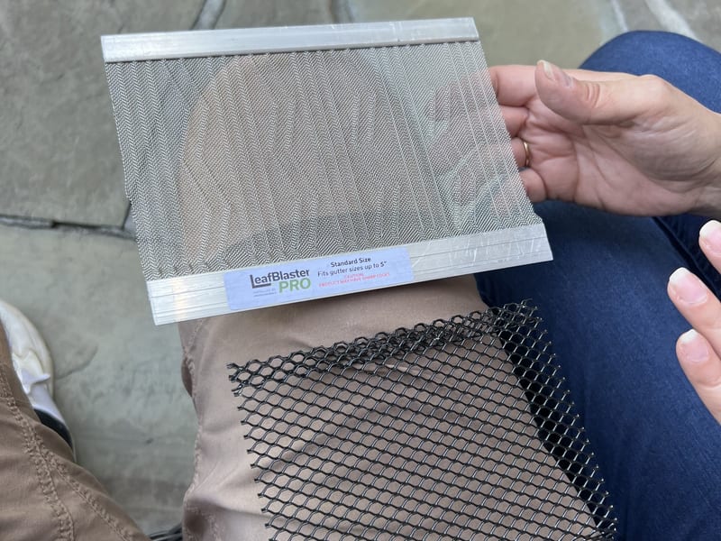 Close-up of a micromesh gutter screen panel held up next to a sample of black mesh guard