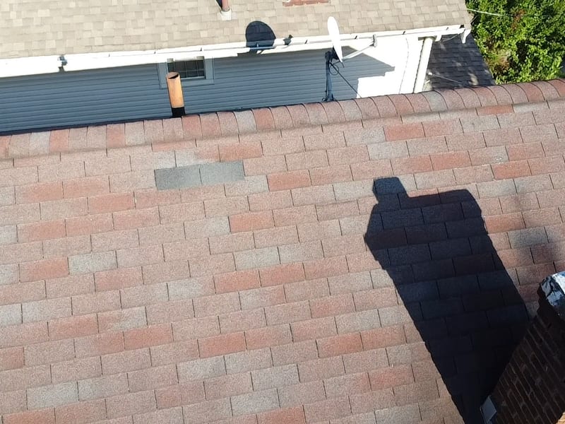 Overhead view of a repaired section of architectural shingles, color-matched against the surrounding roof field