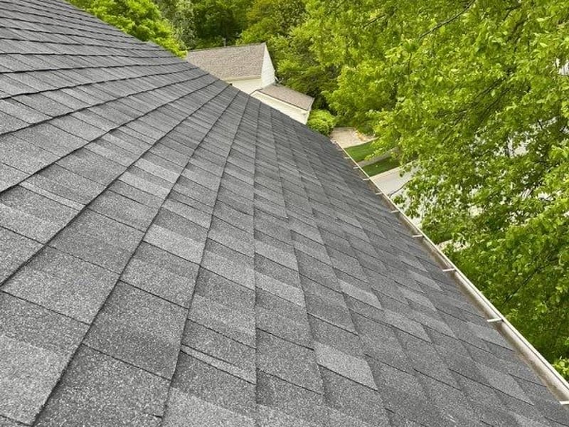 The finished hip in charcoal dimensional shingle with tight even courses and a new gutter line