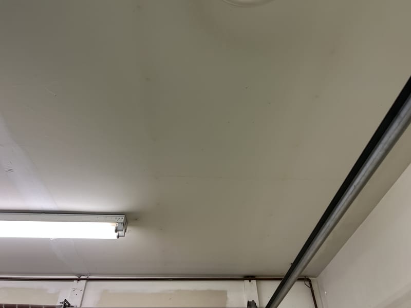 Hairline crack running across a garage ceiling near a fluorescent light fixture