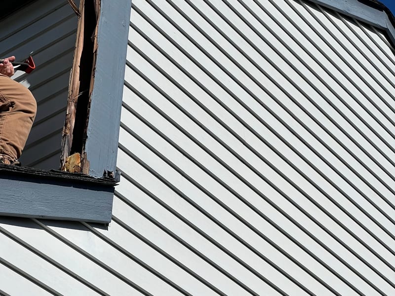 Wide view of a gable end with LP SmartSide siding, corner trim board opened up mid-repair to expose the substrate beneath