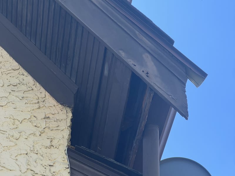 Close view of the overhang where the broken soffit boards left the framing exposed