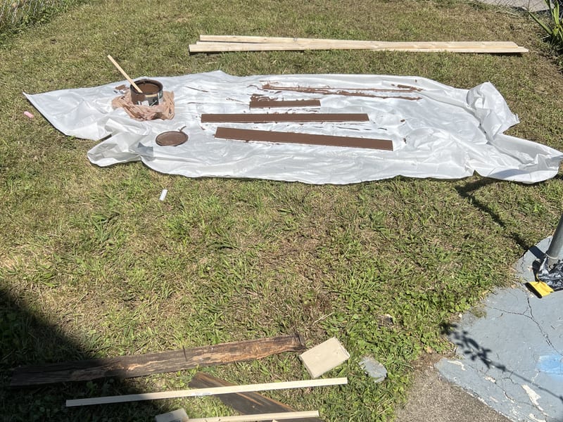 Replacement boards laid out on a drop cloth and painted before installation