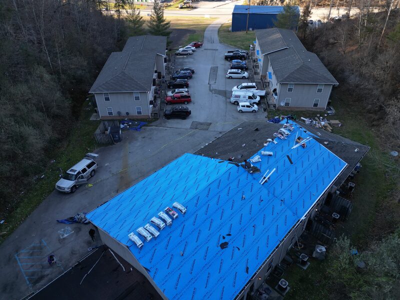 Drone view of the apartment building mid-install with synthetic underlayment rows going down over the decking