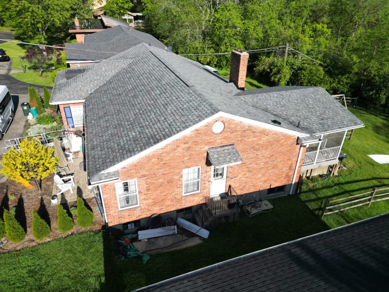 Low-angle side elevation of the finished roofline across all planes, chimney and vents in place