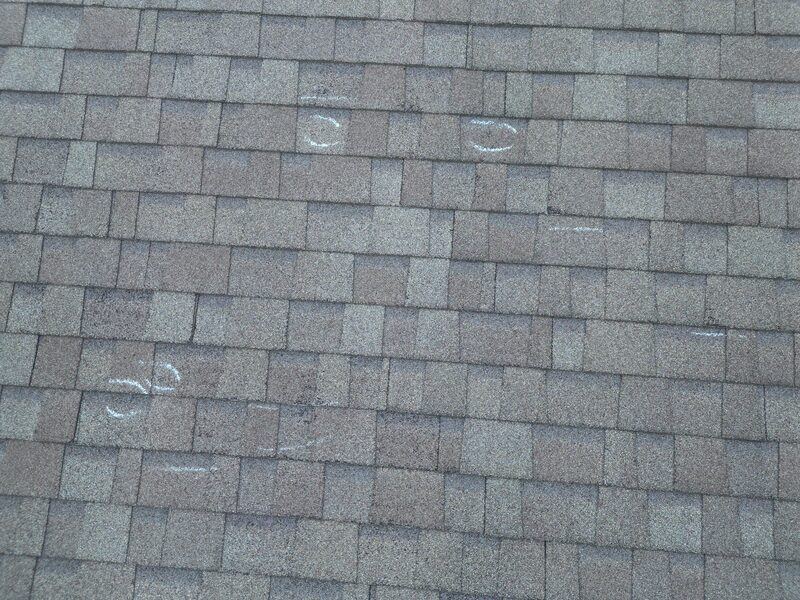 Chalk-marked hail damage during roof inspection