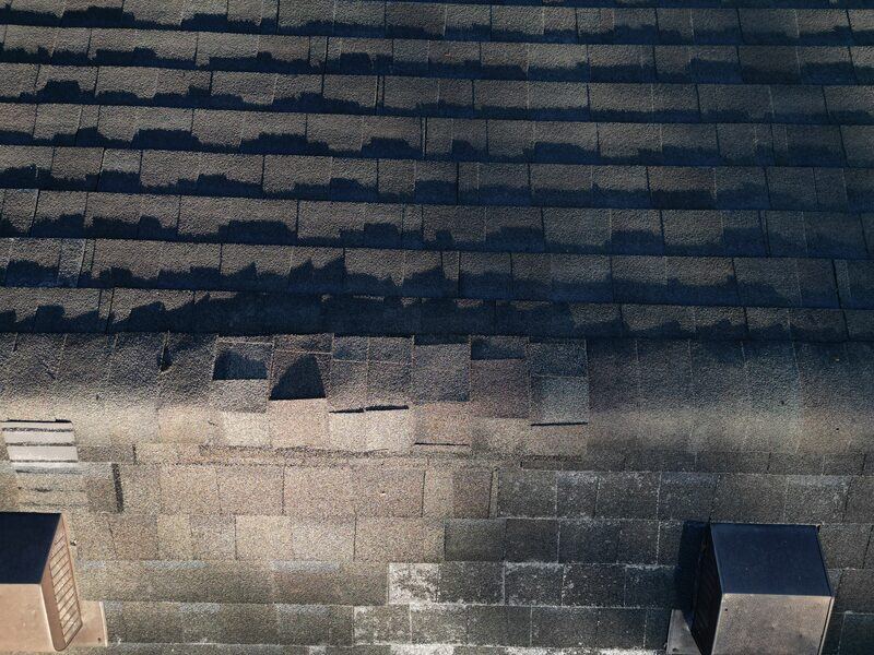 Storm damaged roof with lifted and missing shingles