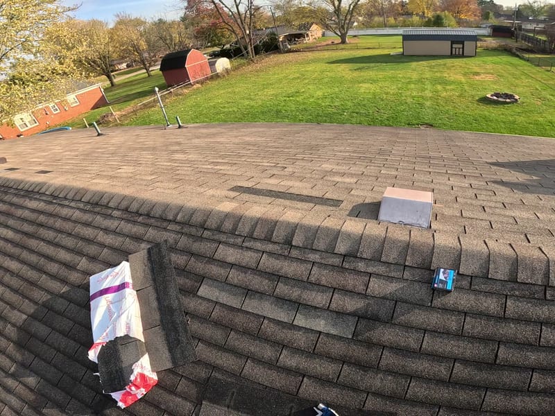 Wide view across the main roof plane in late-afternoon light with the repair area under way
