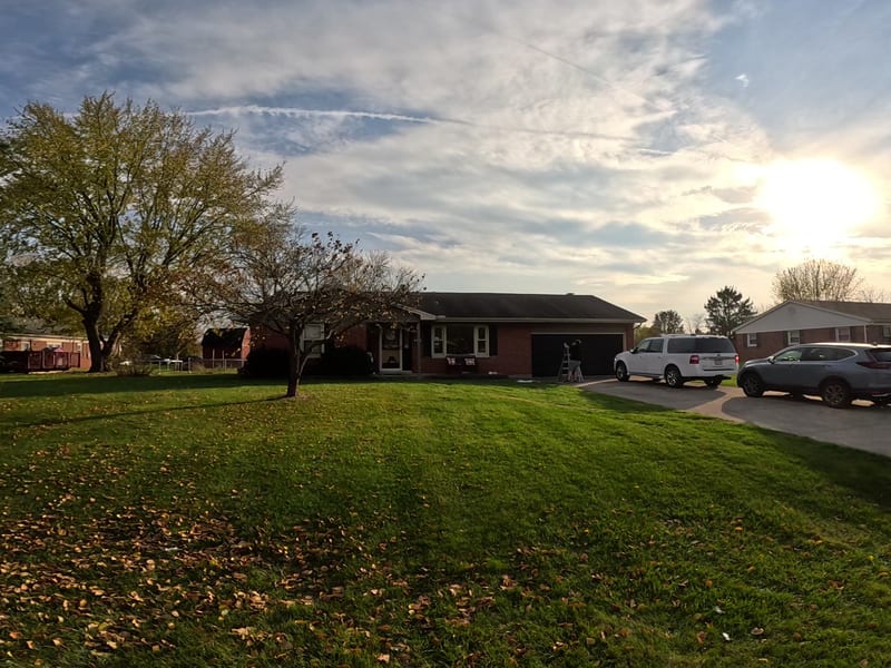 Ground-level view of the finished brick ranch in evening light with the repaired roof in place