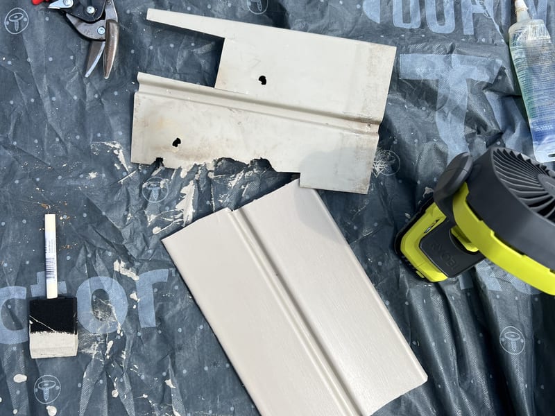 Cut tongue-and-groove soffit boards and hand tools laid out on a drop cloth ready for installation