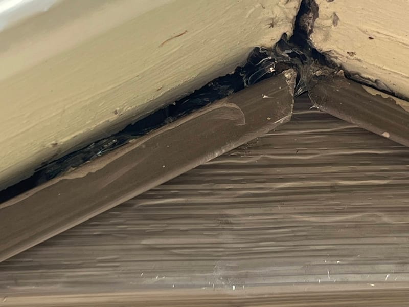 Work-in-progress close-up of the gable peak joint with black sealant worked into the gap between the fascia trim and the J-channel
