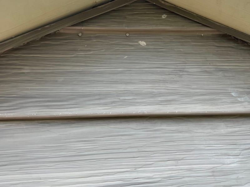 After photo of the gable peak with the J-channel and painted trim sitting tight against the vinyl siding, the joint resealed with no visible gap