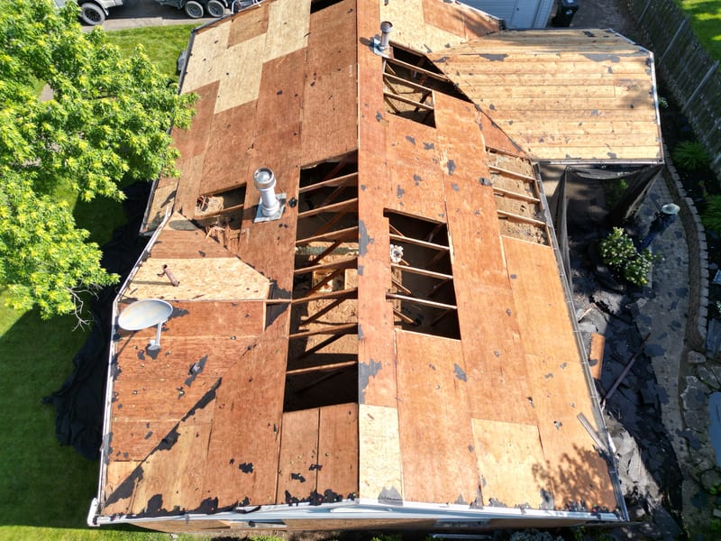 Straight-down view of the entire roof stripped to bare deck, a patchwork of old plank, plywood and fresh sheathing