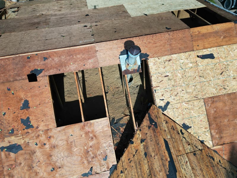 Close decking detail with three generations of substrate side by side: original plank, older plywood and new sheathing