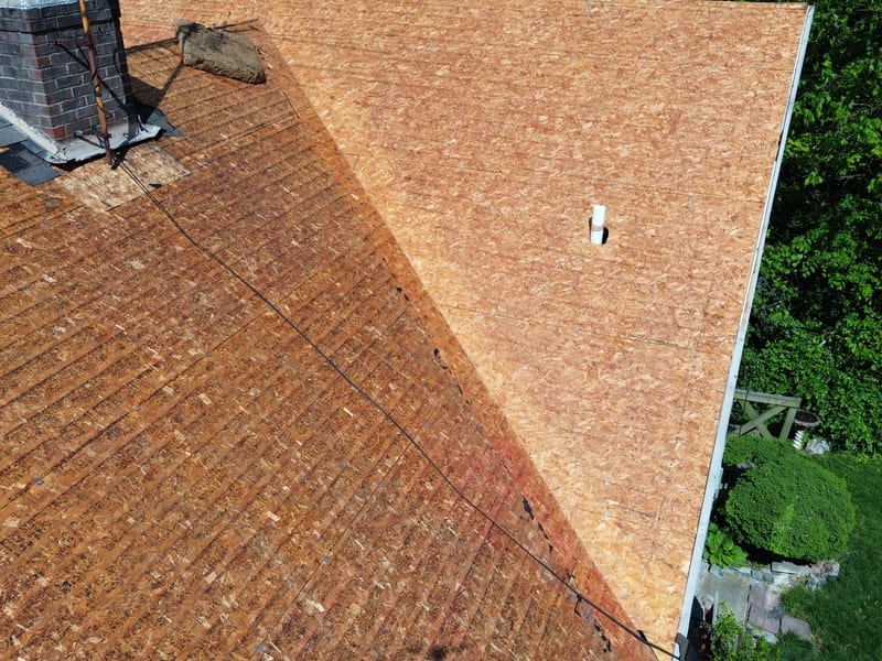 Tight view down the ridge to the brick chimney with the decking fully exposed and old step flashing still in place