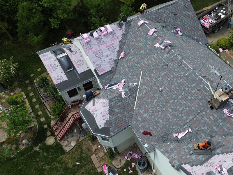 Straight-down aerial with the new shingle field laid across the main roof and only the far wing still on underlayment