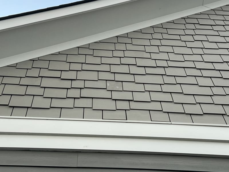 The same front gable with the shake field continuous again and the reattached piece sitting flush and on-course