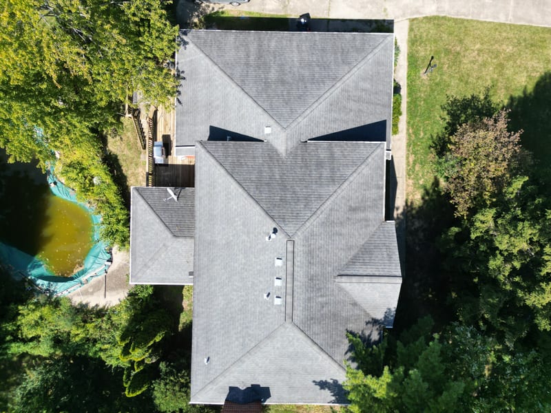 Wide overhead of the same roof before the work, shingles faded and streaked across every plane
