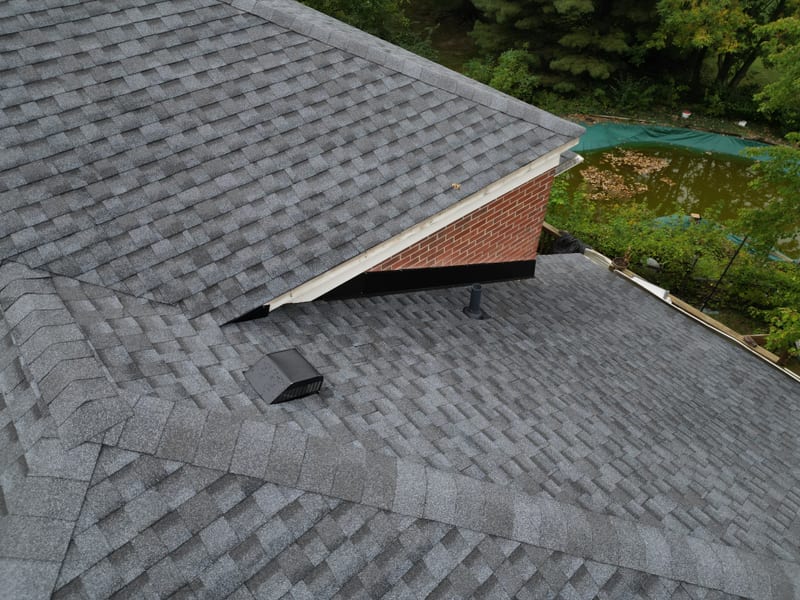 Tight aerial of the finished work with new architectural shingle across the complex hip roof