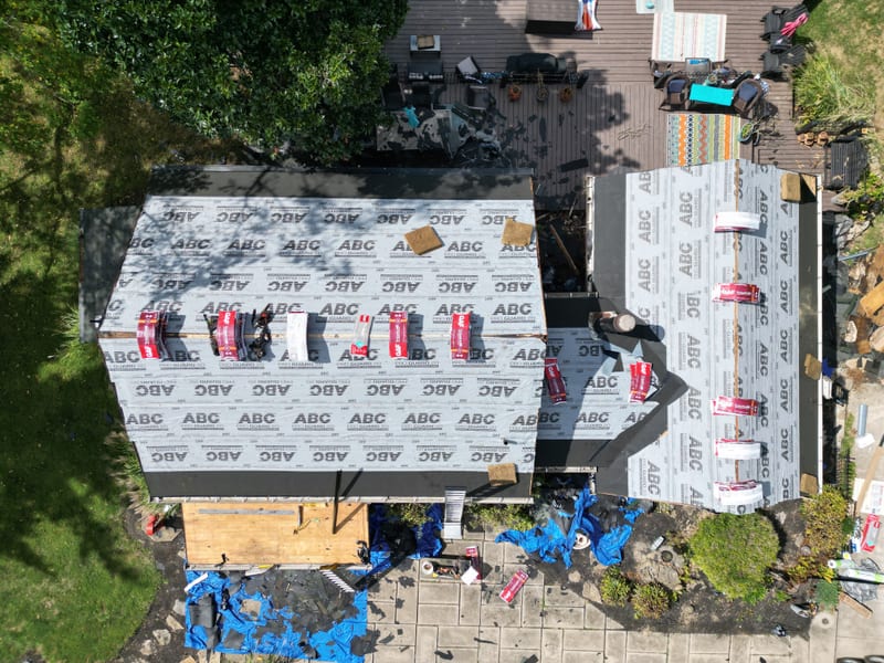 The whole house stripped to deck and dried in at eight in the morning, with new shingle bundles staged across the roof