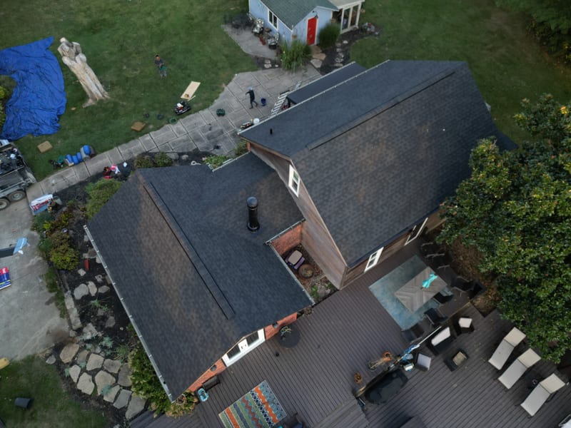 Aerial over the finished house the same afternoon with new charcoal architectural shingles across the full roof