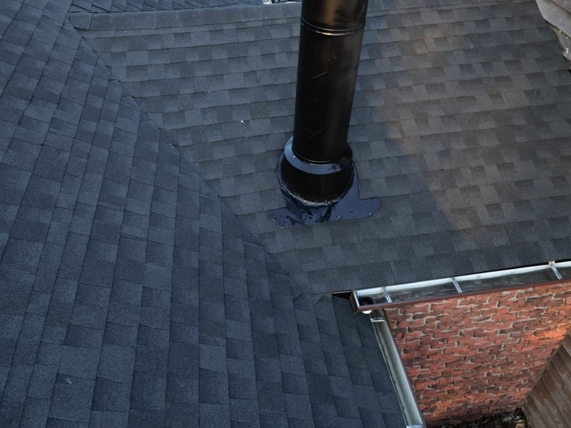 Close view of the finished shingle field around the replaced furnace vent and its new storm collar