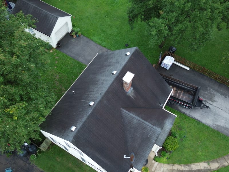 Top-down view of the original roof: weathered, streaked shingles across all seven facets with the masonry chimney mid-slope