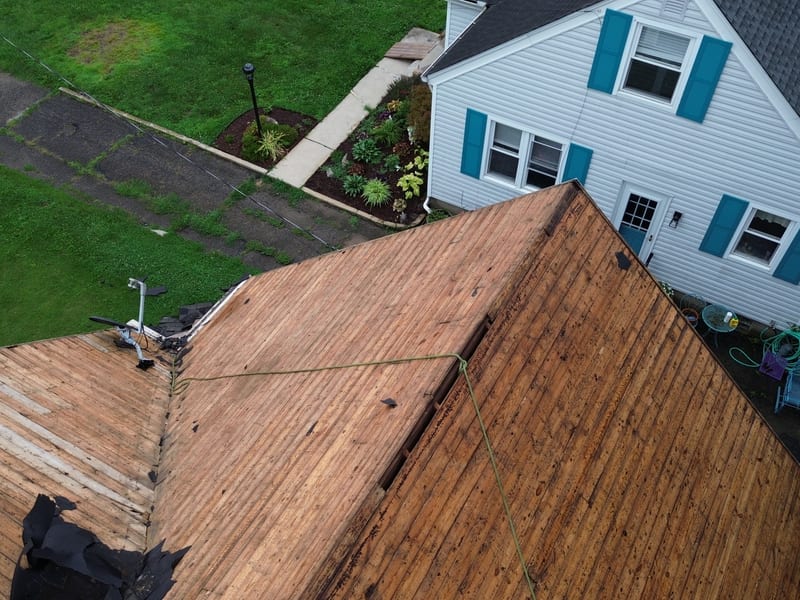 Tight aerial down the ridge showing the old one-by plank decking board by board, including the gaps and deteriorated boards
