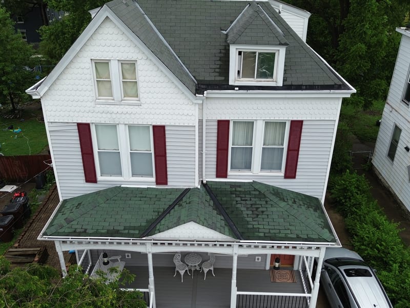 Three-story white Victorian with a steep mansard, dormers and a flat upper roof, shot from the front