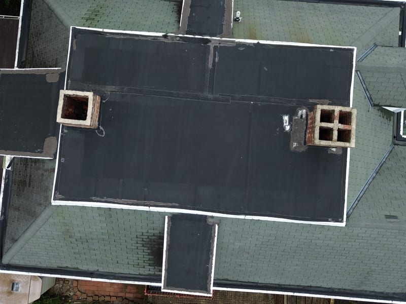 Straight-down view showing all three roof systems in one frame: shingle mansard, flat membrane and dormer caps