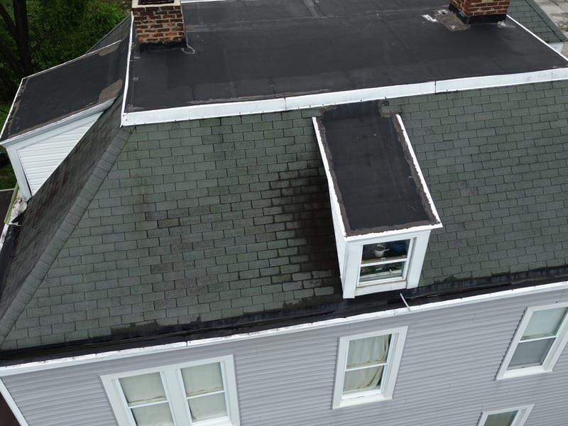 A dormer bay capped in rubber membrane rather than shingle, the condition the job converted back to shingle
