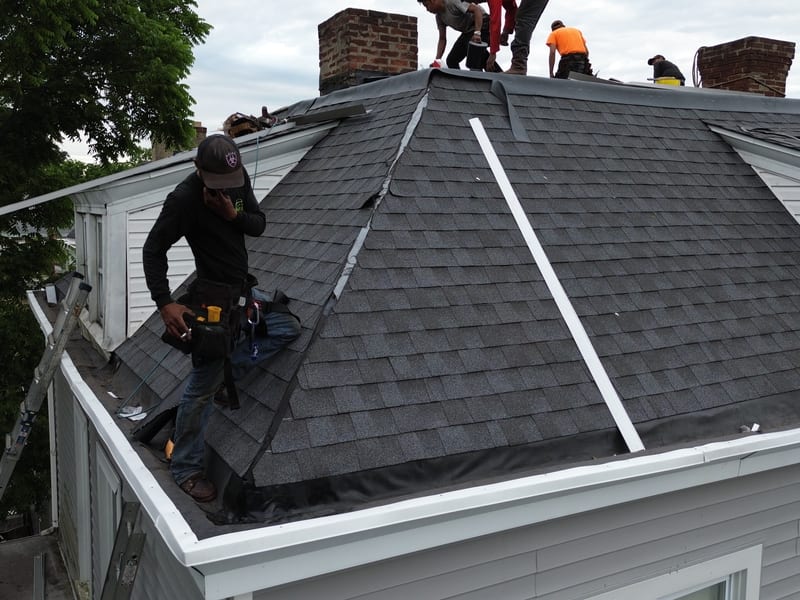 Install day on the mansard with the crew running new pewter-grey architectural shingles up the hip