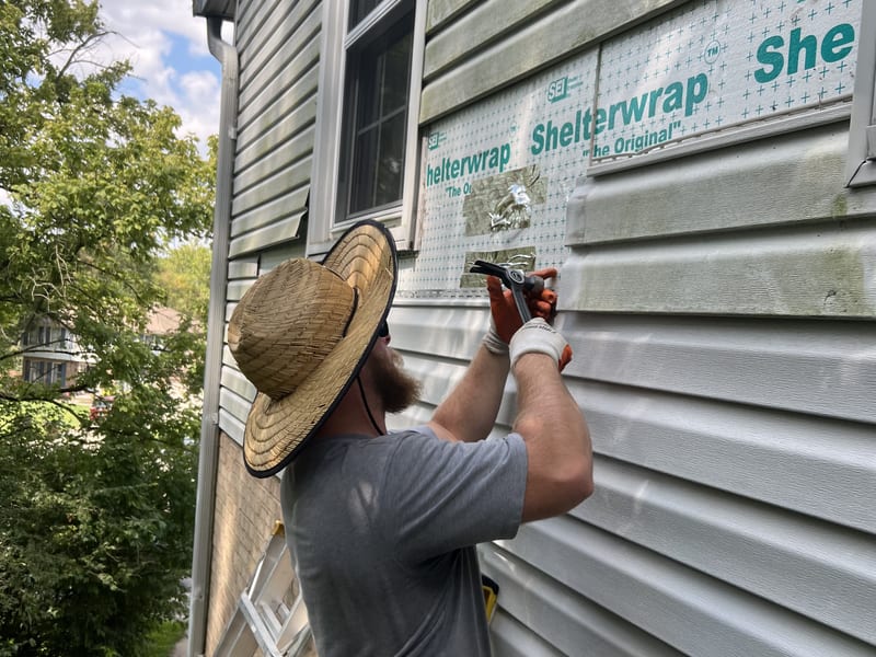 Installer nailing a new siding course over the fresh house wrap patch