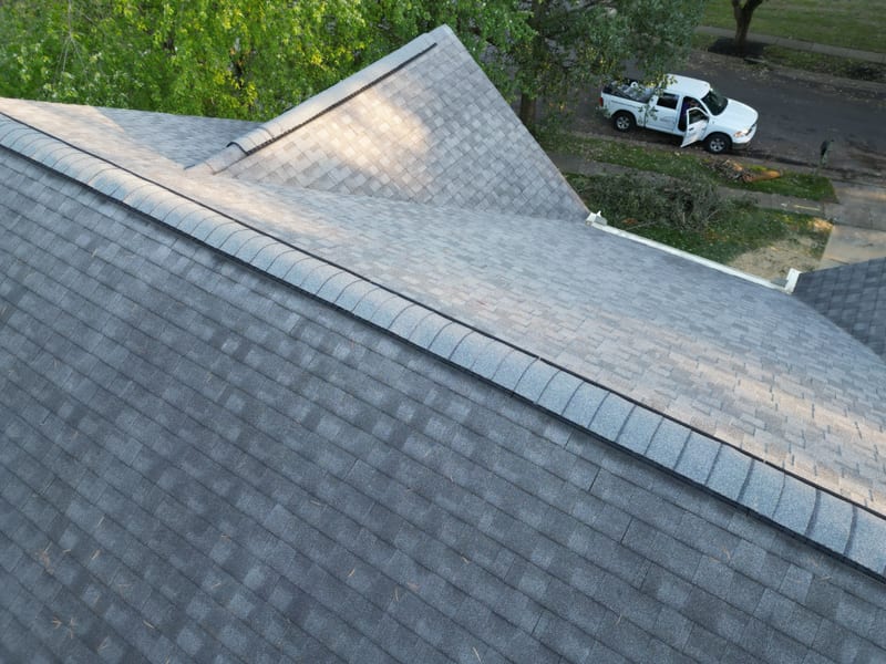 The completed replacement roof in fresh gray shingles with a new ridge vent run